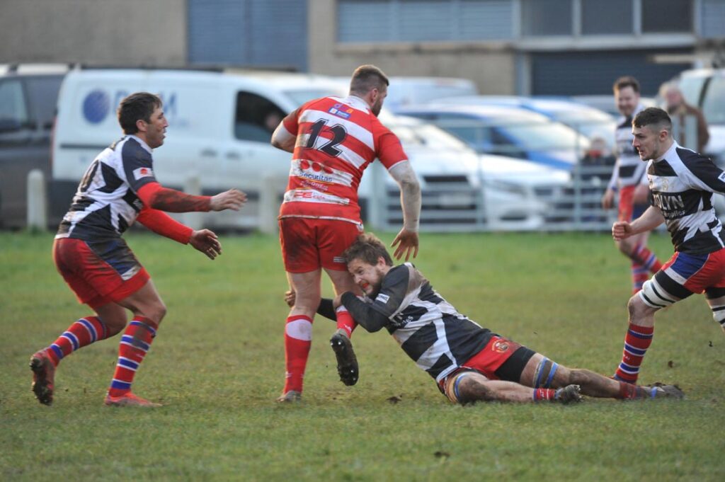 Pencoed’s Tom Geere makes a tackle with Gavin Henson and Jamie Burton move in to support.
