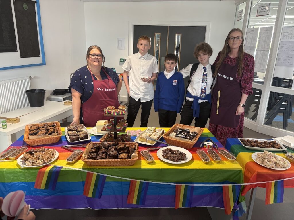Mrs Smith and Mrs Jackson with team members at a special Pride bake sale, complete with rainbow muffins.