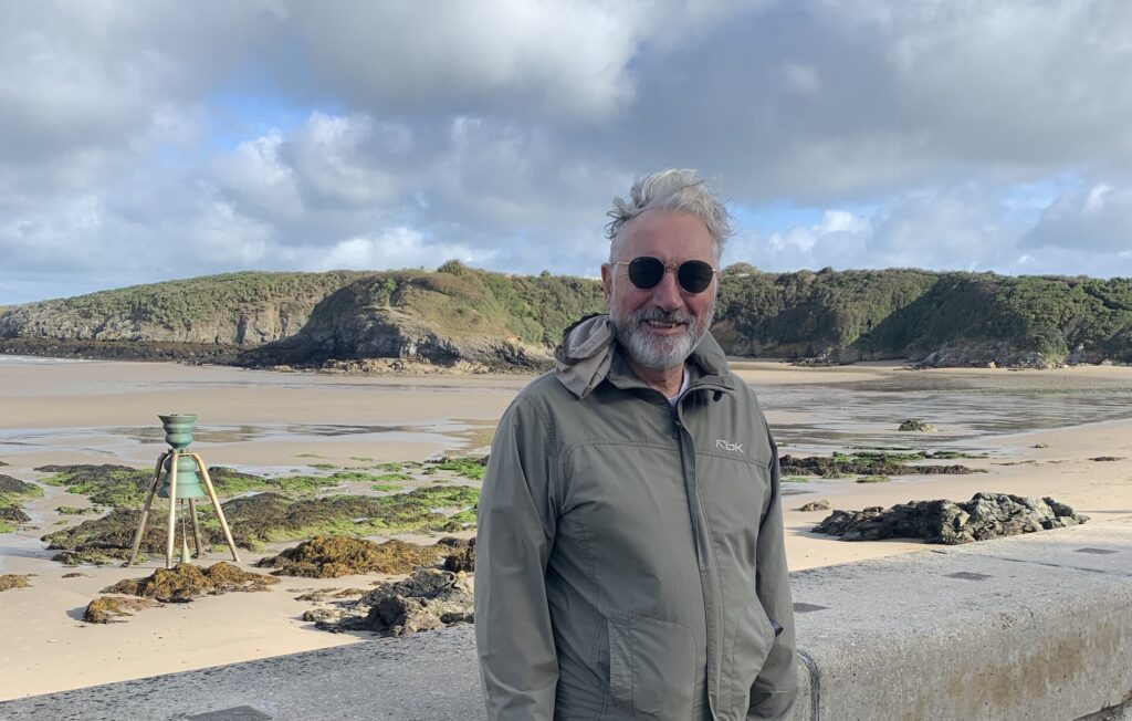 Brian Mayne at Cemaes Bay, with the bell in the background.